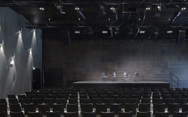 Großer Saal mit Reihenbestuhlung, Blick von hinten auf die Bühne.