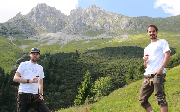 Zwei Männer in Lederhosen in den Tiroler Bergen mit dem Latschenlikör.