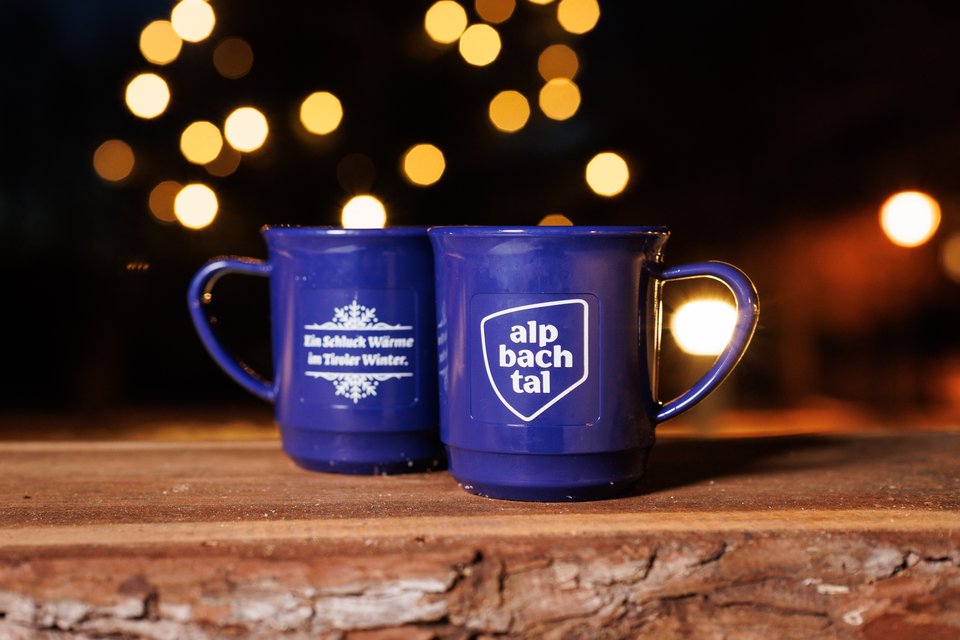 Zwei blaue Porzellantassen mit dem Logo von Alpbachtal Tourismus