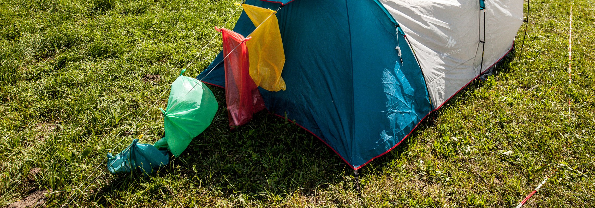 An einem Zelt hängen verschiedenfarbige Säcke zur Abfalltrennung.
