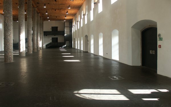 Große Säulenhalle des Salzlager. Auf der rechten Seite ist eine dicke weiße Wand mit einer schweren Tür und vielen Fenstern, links einige Säulen.